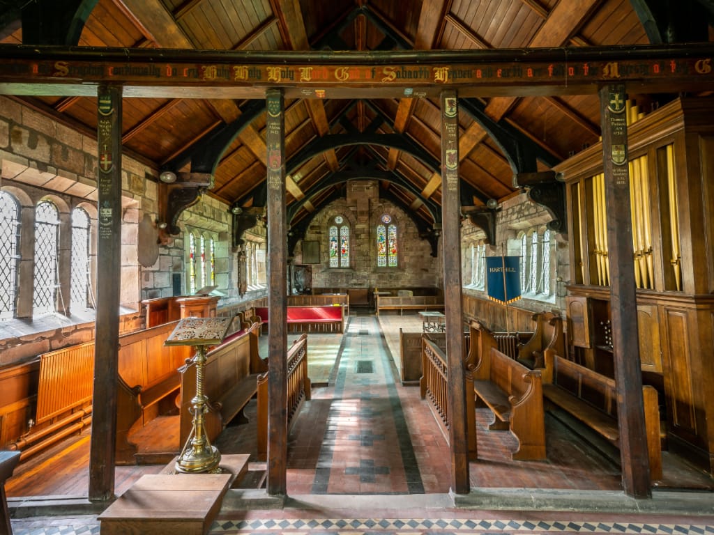 Interior view of Harthill Church showing wooden beams, pews, and tiled flooring