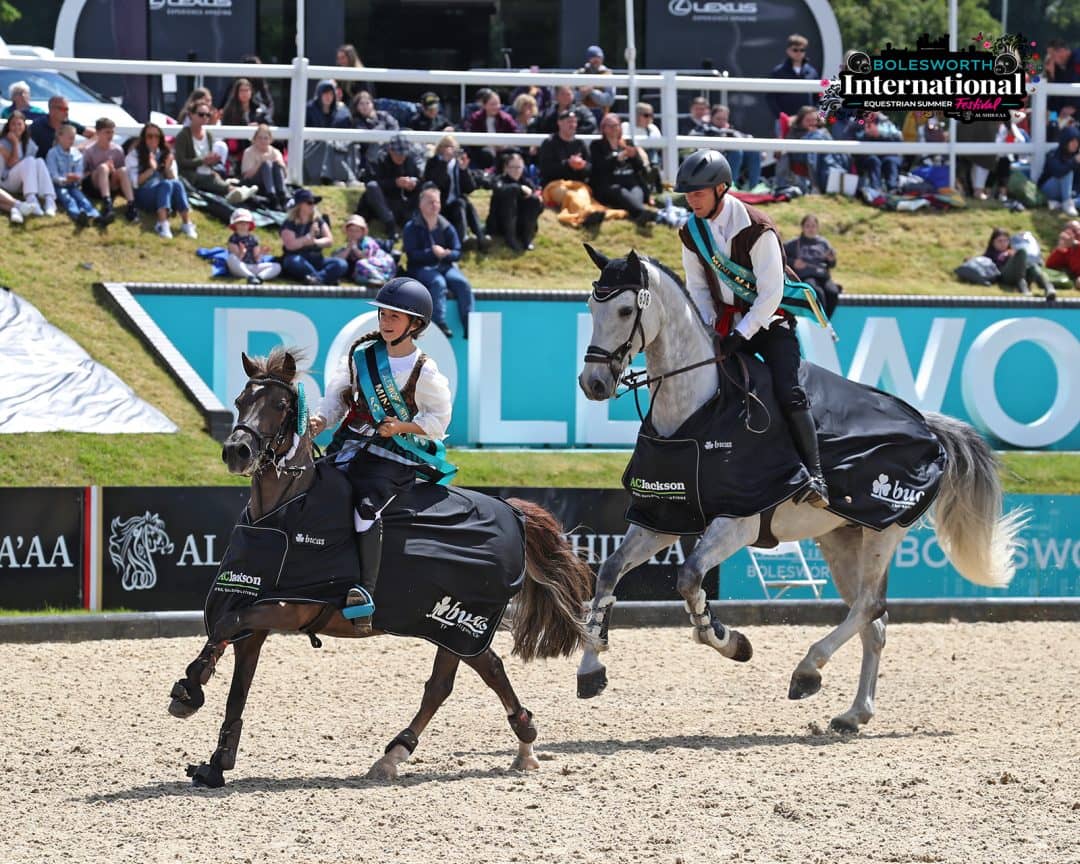 Two winning riders performing a celebratory parade together after an equestrian competition