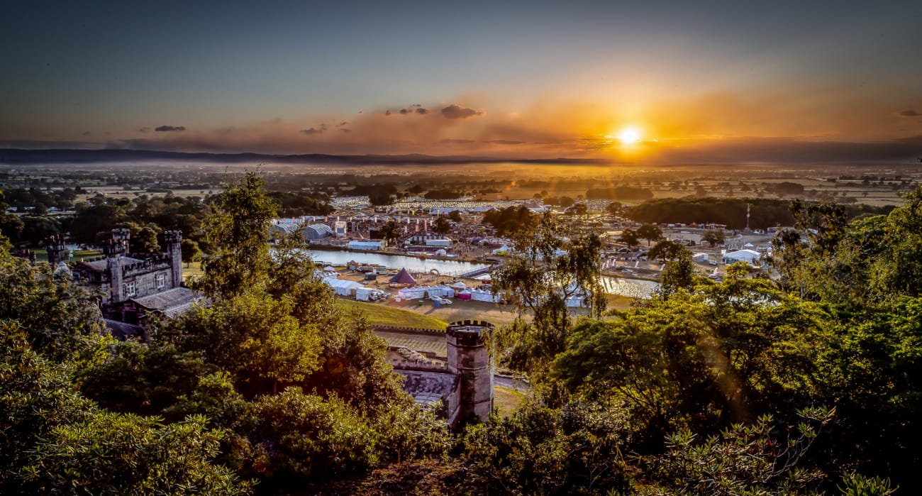 A breathtaking sunset over Bolesworth, showcasing the estate, festival grounds, and lush countryside.