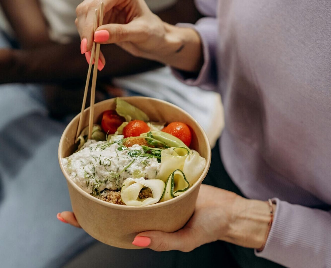 Image of a women holiday a takeaway pot of street food, including noodles, vegtables and sauce.