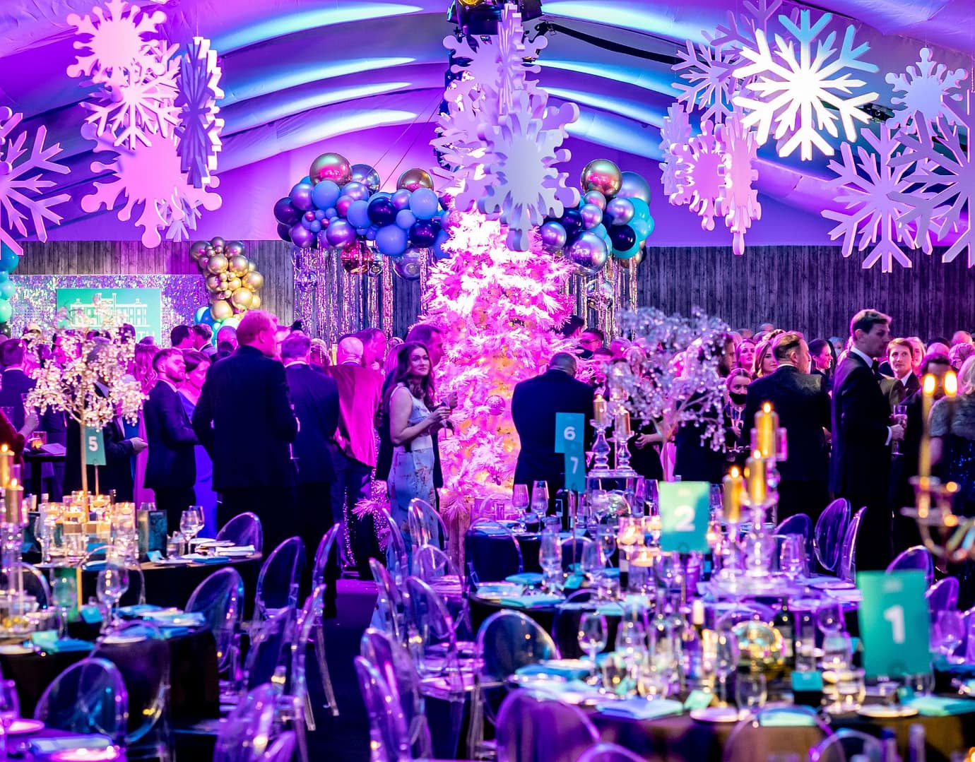 Festively decorated venue with snowflake designs, sparkling lights, elegant table settings, and guests enjoying the vibrant atmosphere.
