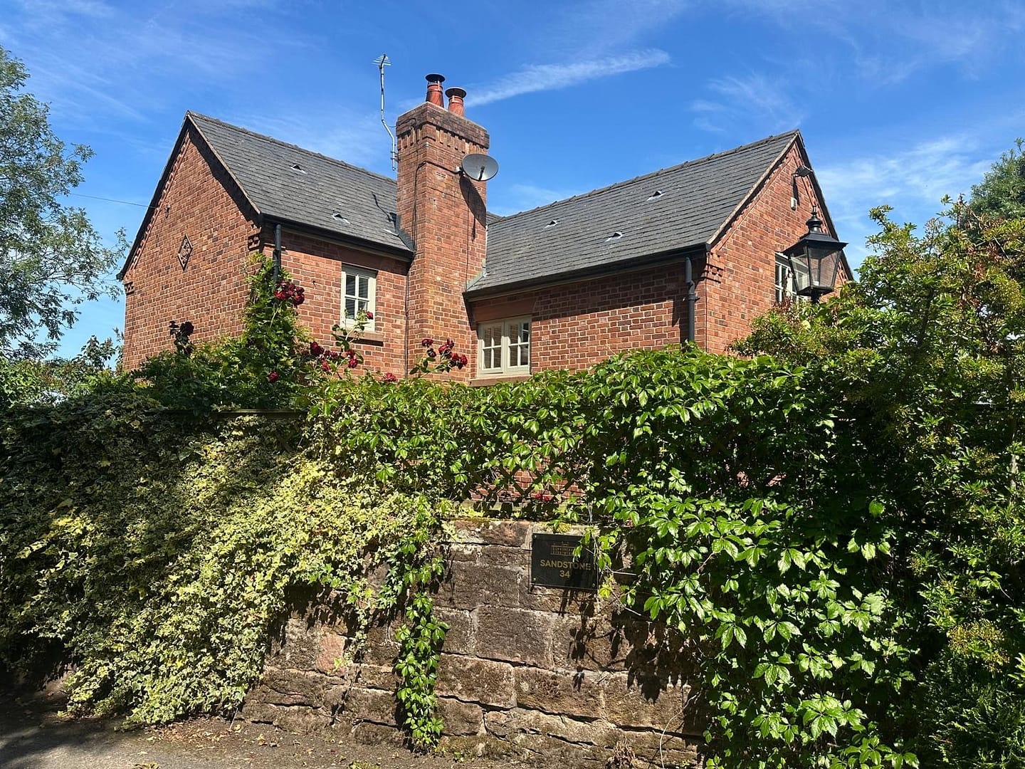 Detached house behind a wall with greenery in Buwardsley, Cheshire