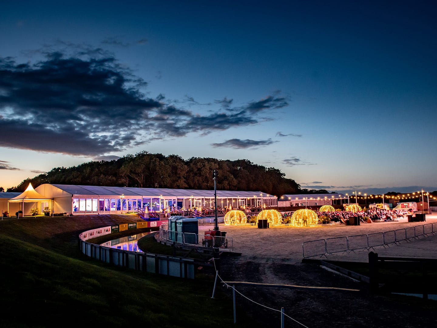 Nighttime view of Bolesworth's illuminated marquee and event space with glowing decorative lights and seating.