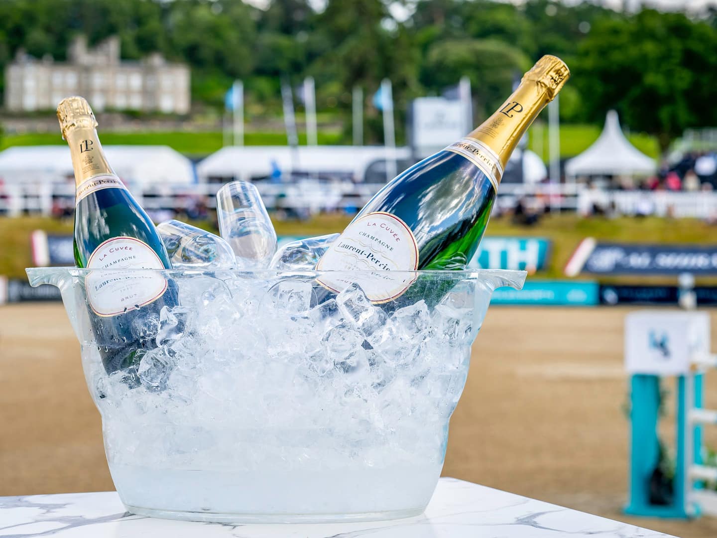 A champagne bucket filled with ice and two bottles, with an arena in the background.