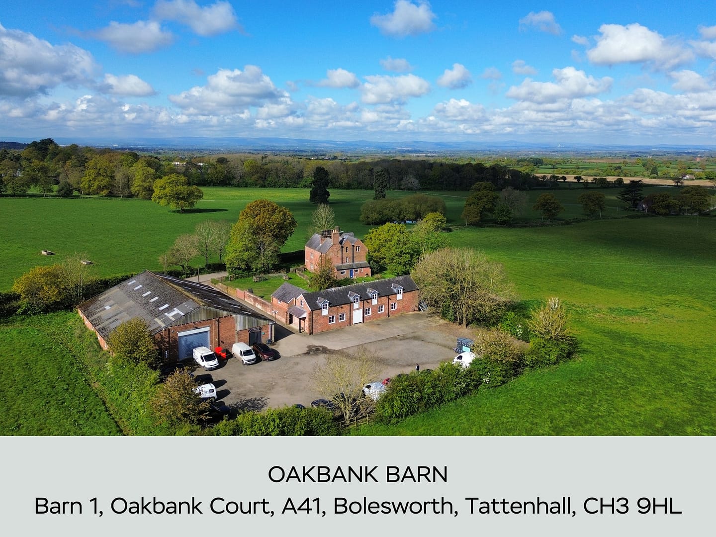 An aerial view of Oakbank Barn, a converted barn complex with modern and traditional architecture, set in expansive green countryside near Bolesworth, Tattenhall.