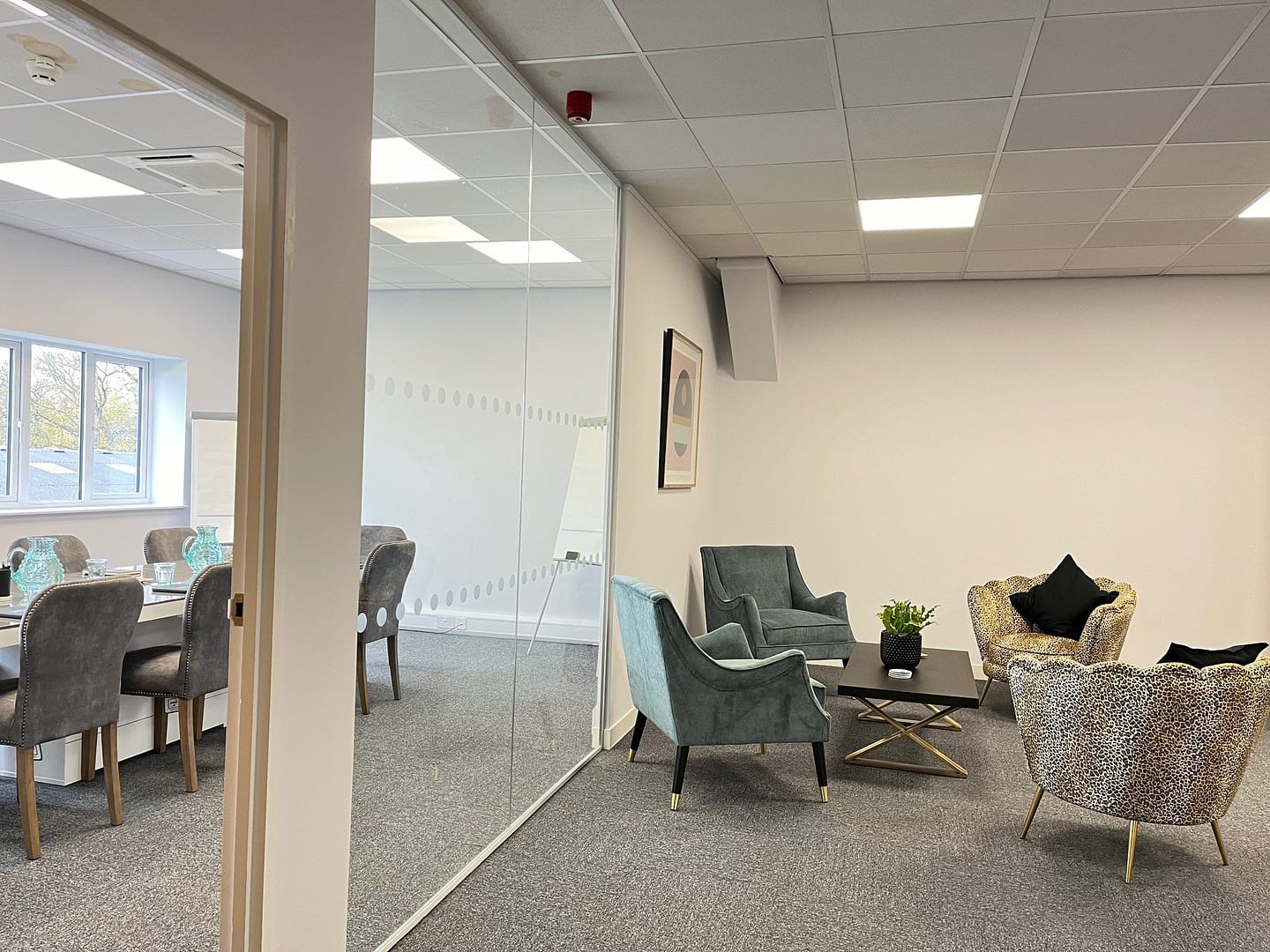 Open plan meeting space two separate spaces, showing a boardroom with table and chair and sitting area for comfy chairs and coffee table
