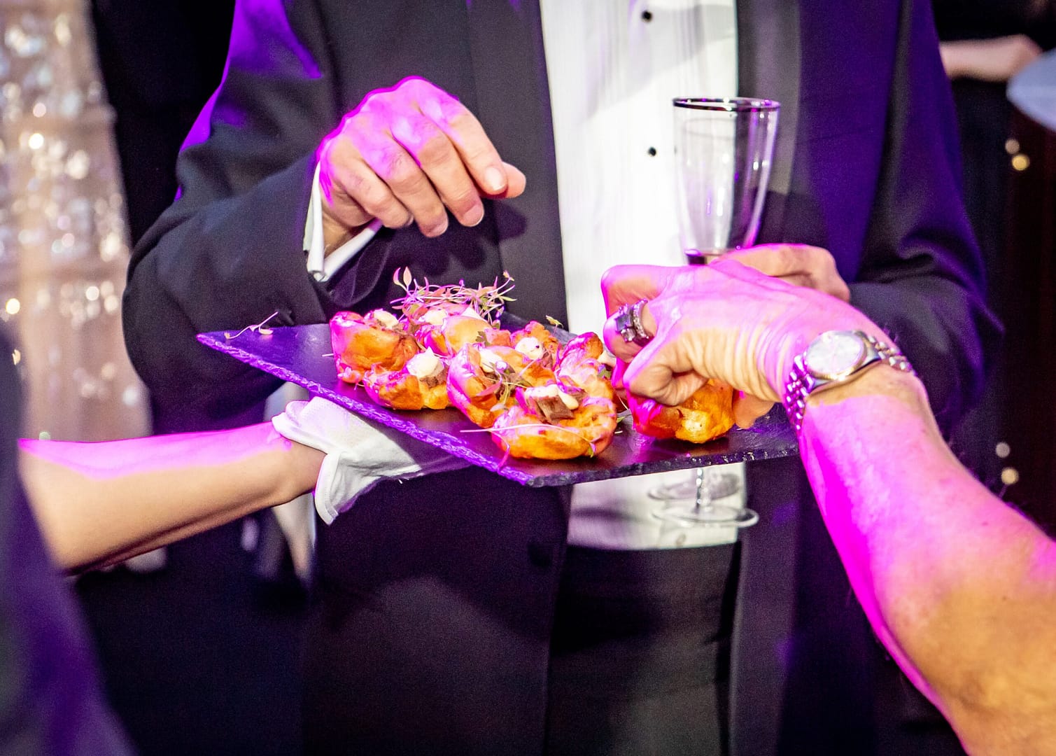 A tray of canapes being served with people's hands ready to pick one up