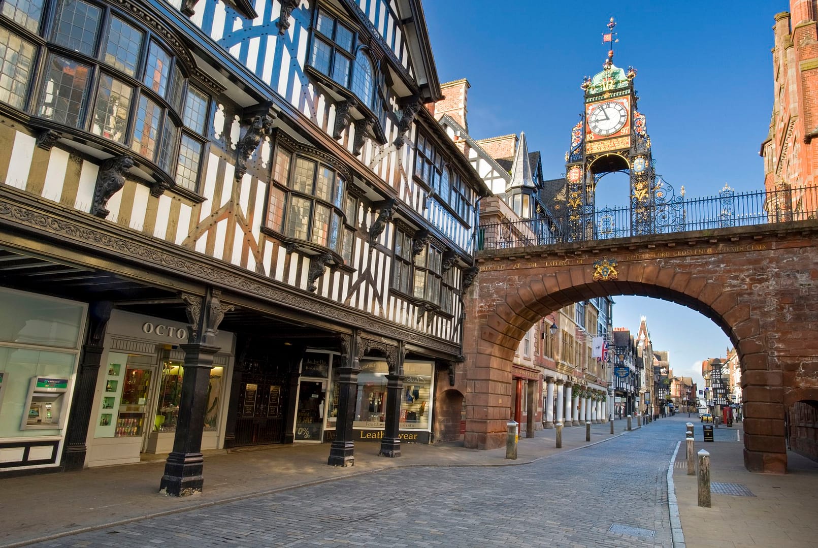 Historic Eastgate Clock in Chester, UK, standing above the medieval city walls with half-timbered Tudor-style buildings lining the streets.