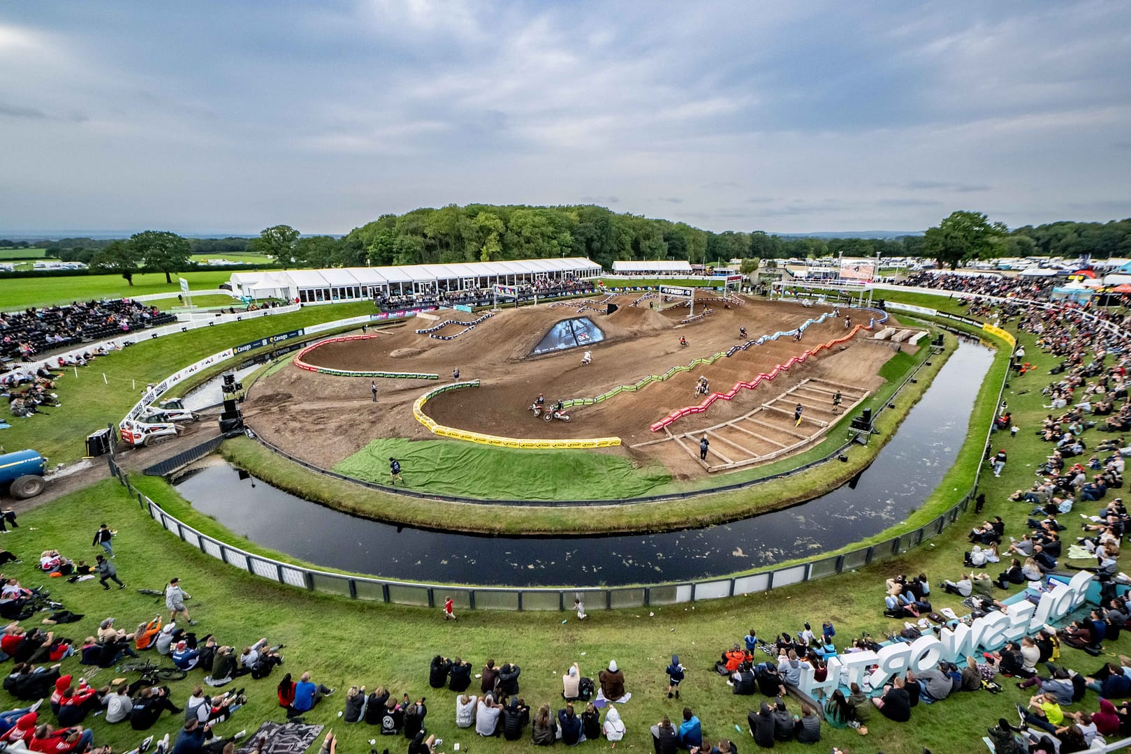 Aerial view of Bolesworth's amphitheater-style pavilion for motorsport, featuring a moat surrounding the pavilion, audience seating, and a marquee backdrop.