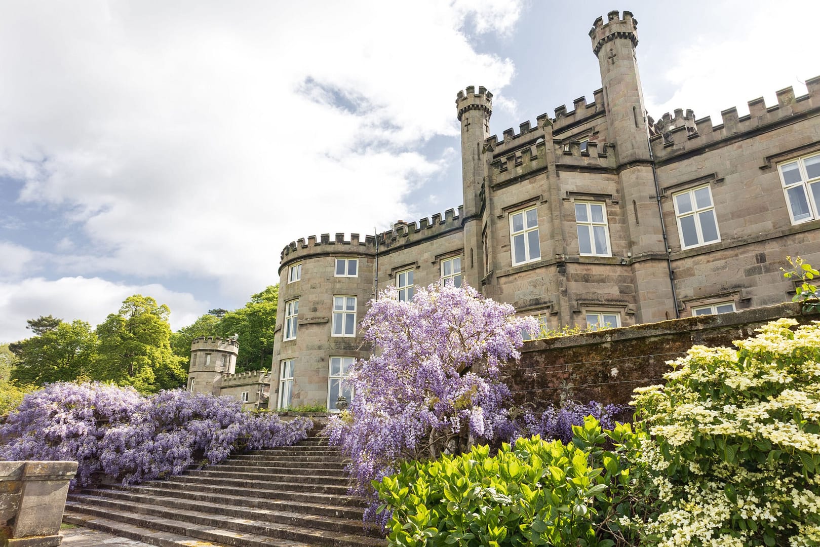 Exterior of Bolesworth Castle surrounded by the purple coloured flower, wisteria.