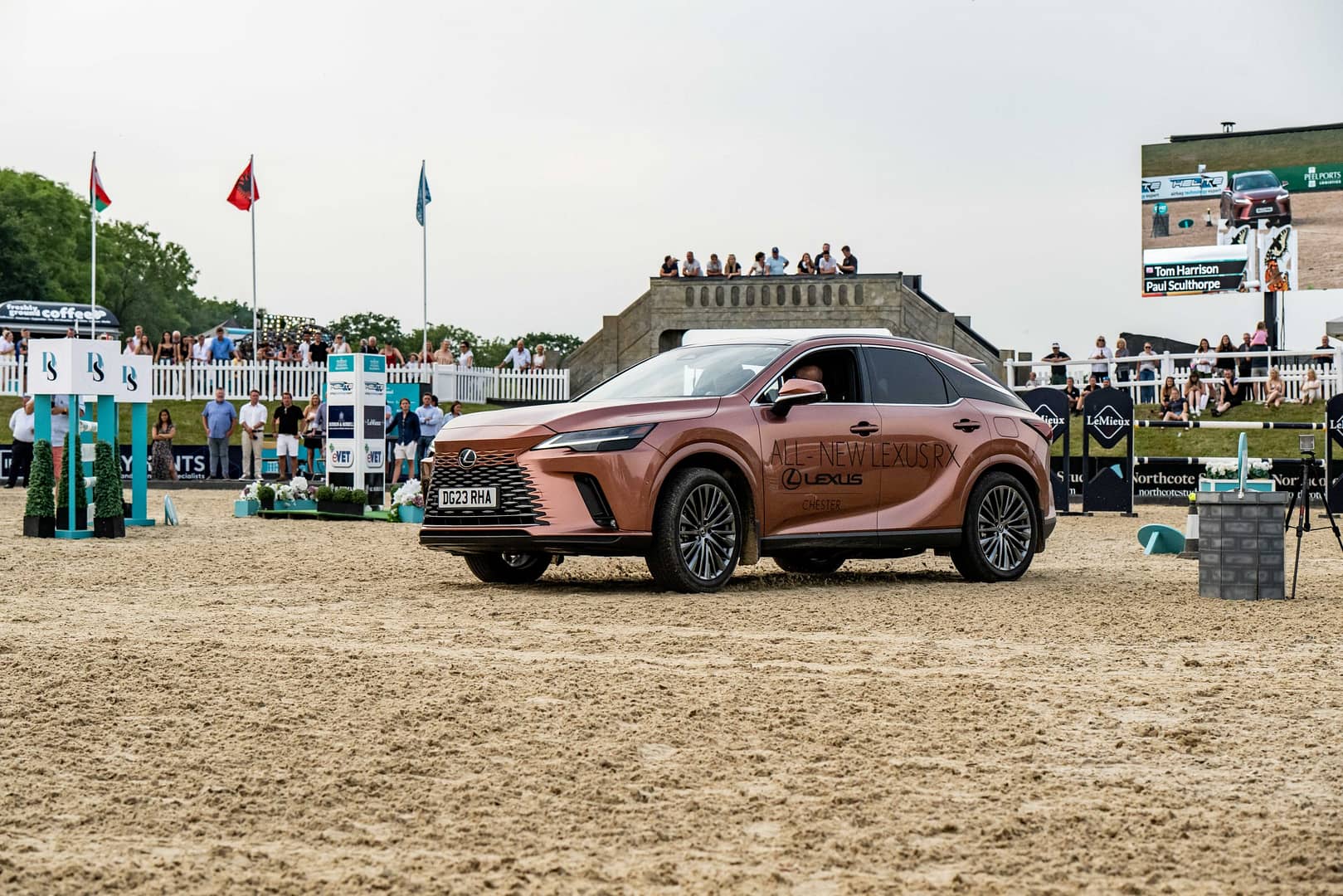 A Lexus car is presented on the Bolesworth equestrian show ground, with the Bolesworth estate and a crowd of spectators in the background.