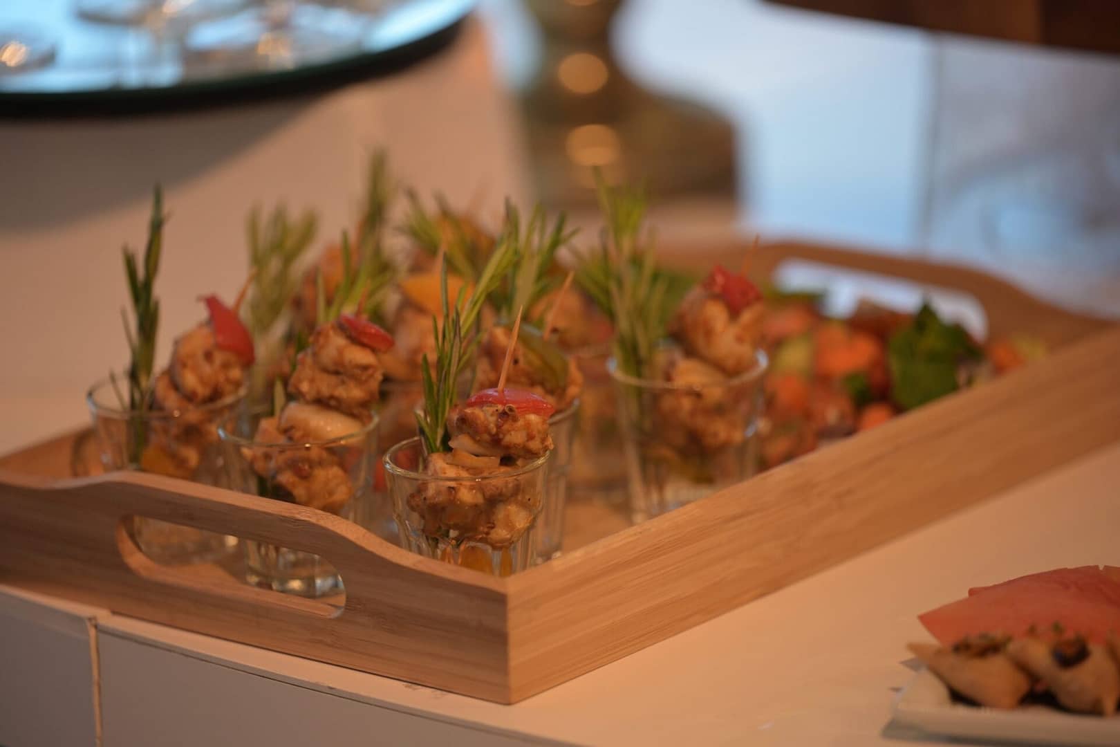 Wedding canapés of chicken with garnish, elegantly displayed on a wooden tray on a wedding table setting.