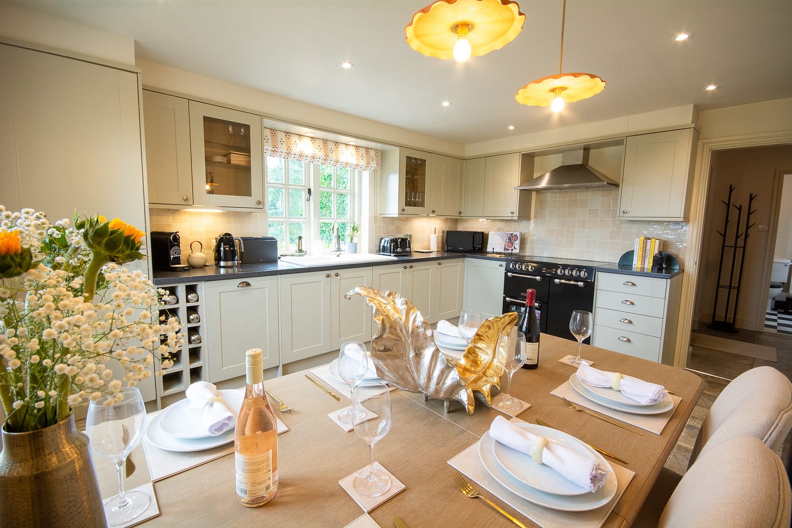 Kitchen diner with a dining table dressed with plates, napkin and a bottle of Rose and red wine.