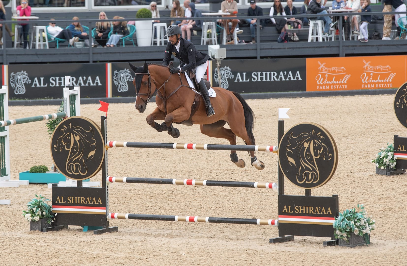 Winning Al Shira'aa equestrian rider and horse, jumping over a high fence within a showjumping competition.