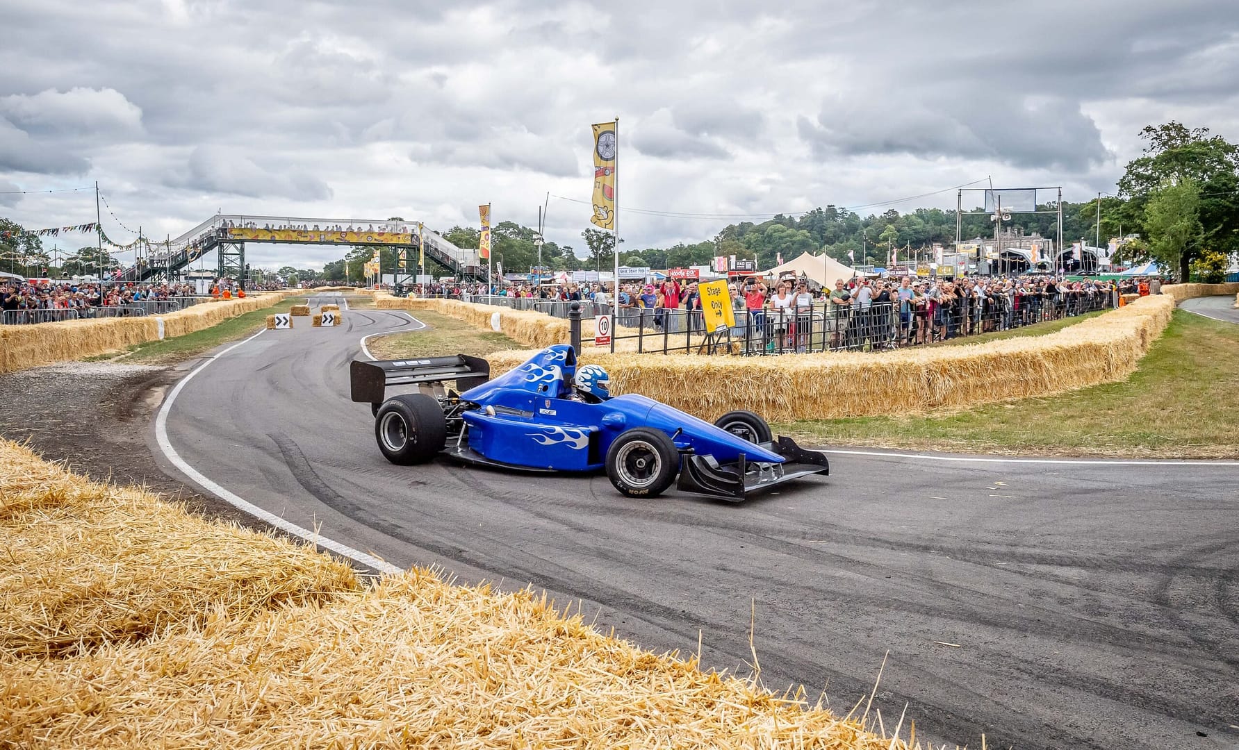 Blue racing car on an internal road circuit with crowds watching