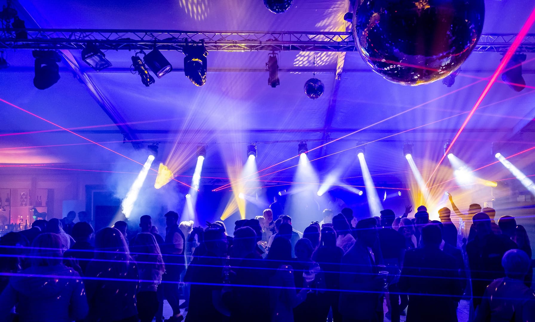 A vibrant nightlife scene at the Bolesworth International Horse Show, featuring a lively crowd, dazzling laser lights, and a high-energy party atmosphere under a marquee.