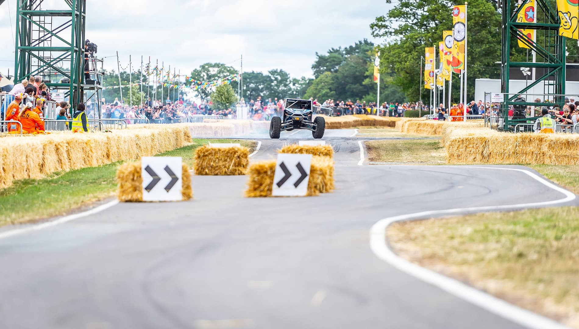 A motor vehicle racing up an internal road at Bolesworth during Carfest North festival with crowds cheering