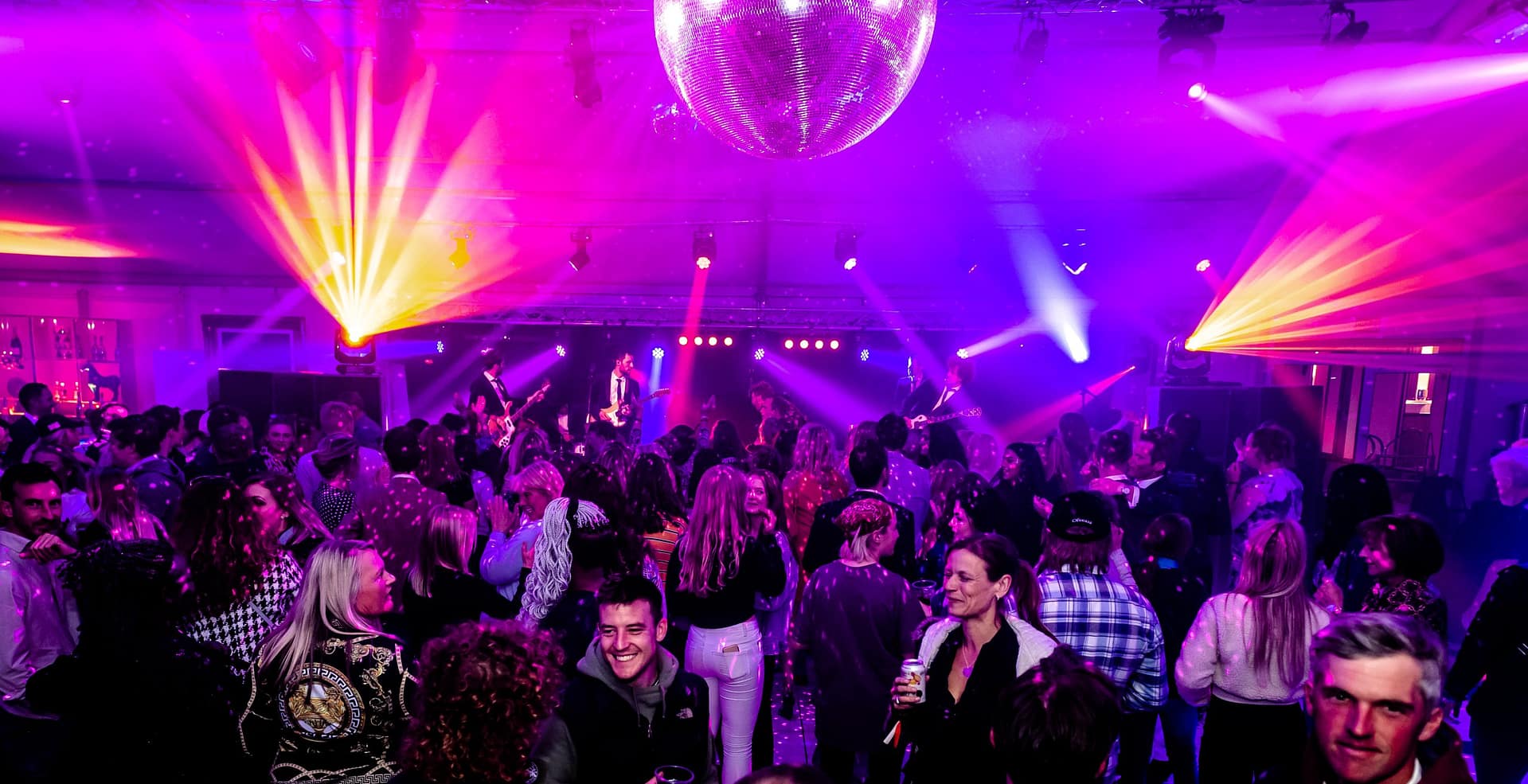 Electrifying evening under the disco ball, where a crowd of people enjoy music and dancing.