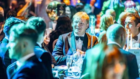 Guests in formal attire enjoying the Bolesworth Elite Auction 2024 gala dinner, engaging in conversation over a candlelit table setting.