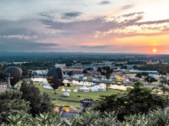 A scenic view of an event venue with tents and greenery, set against a dramatic sunset sky.