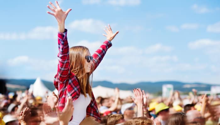 Excited festivalgoers at Together Again Festival 2025, with a young woman on shoulders cheering in the crowd under blue skies. The Bolesworth Castle festival atmosphere is filled with music, energy, and summer vibes.