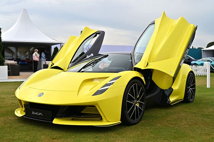A stunning yellow Lotus Evija electric hypercar with butterfly doors open, showcased on the lawn at Bolesworth International Horse Show.