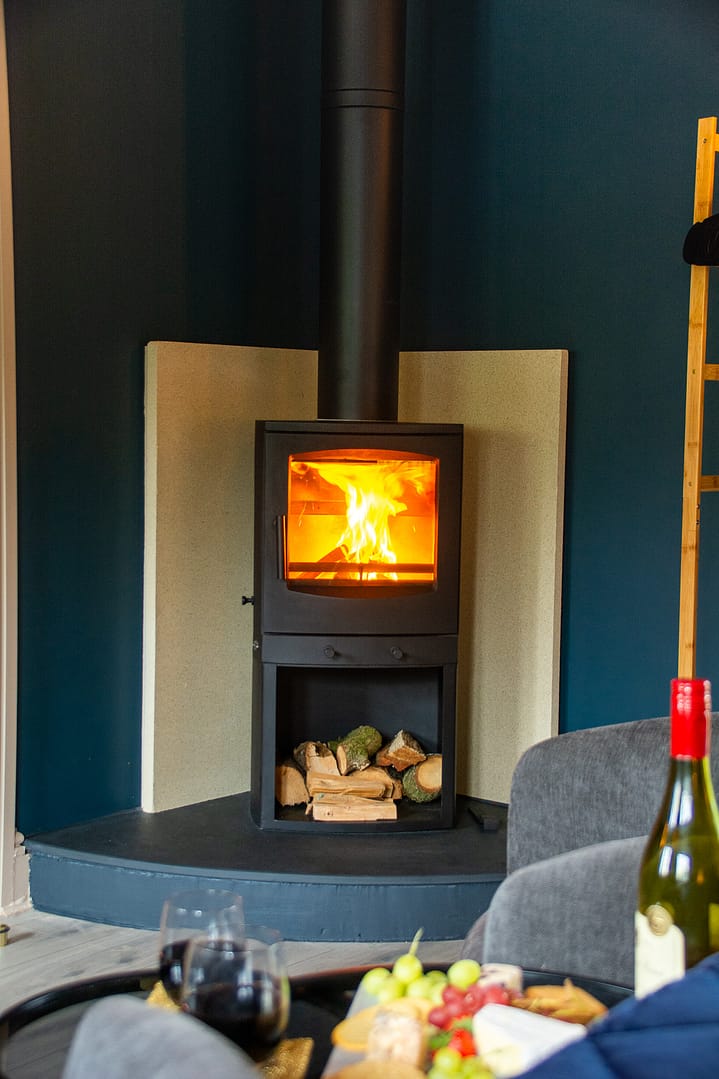 Log burner with a bottle of wine, two wine glasses and a plate of cheese