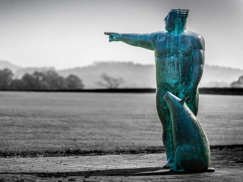 A statue in Tattenhall pointing into the distance, set against an open rural landscape.